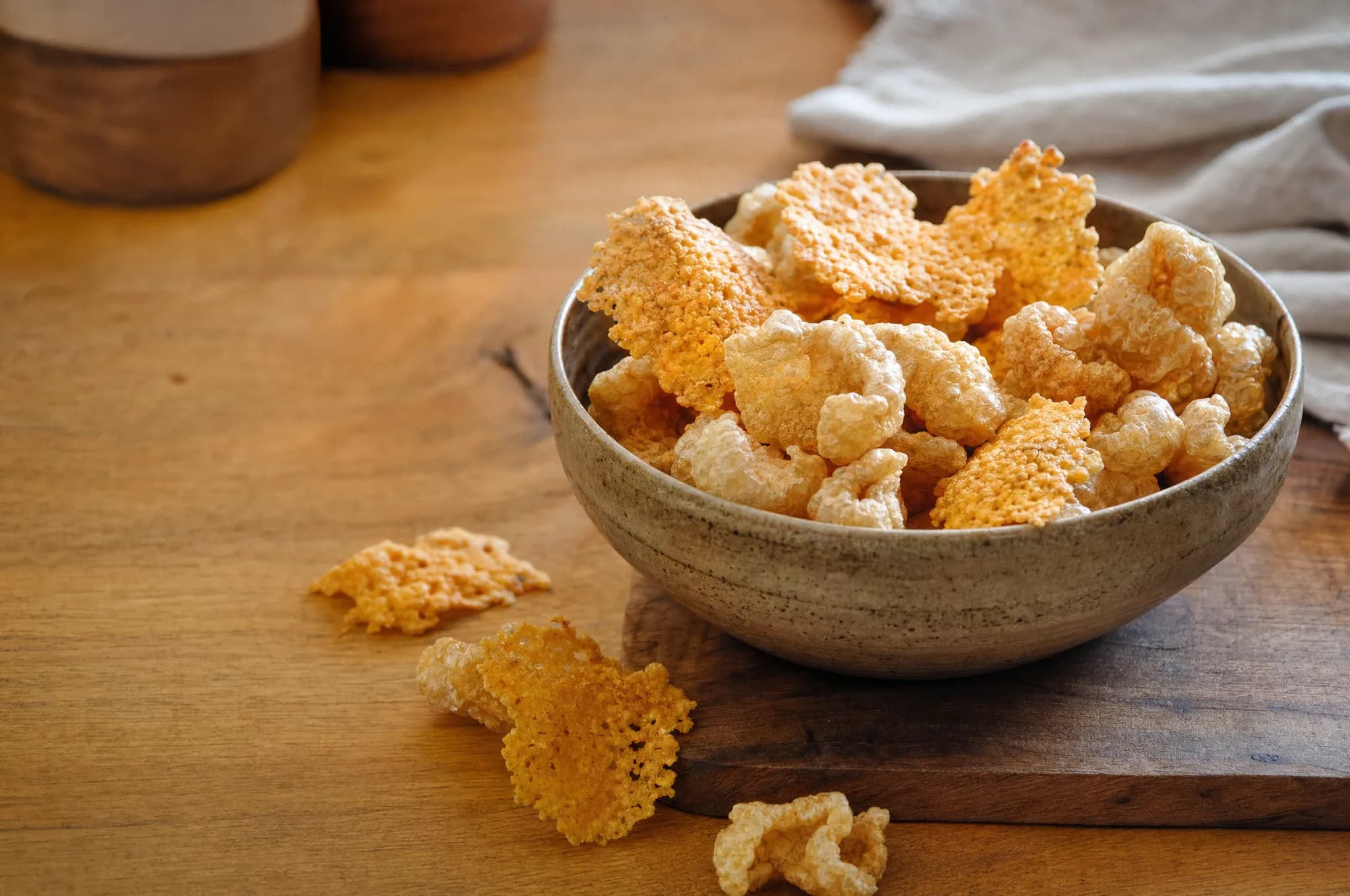 A bowl of golden cheese crisps and pork rinds on a kitchen counter