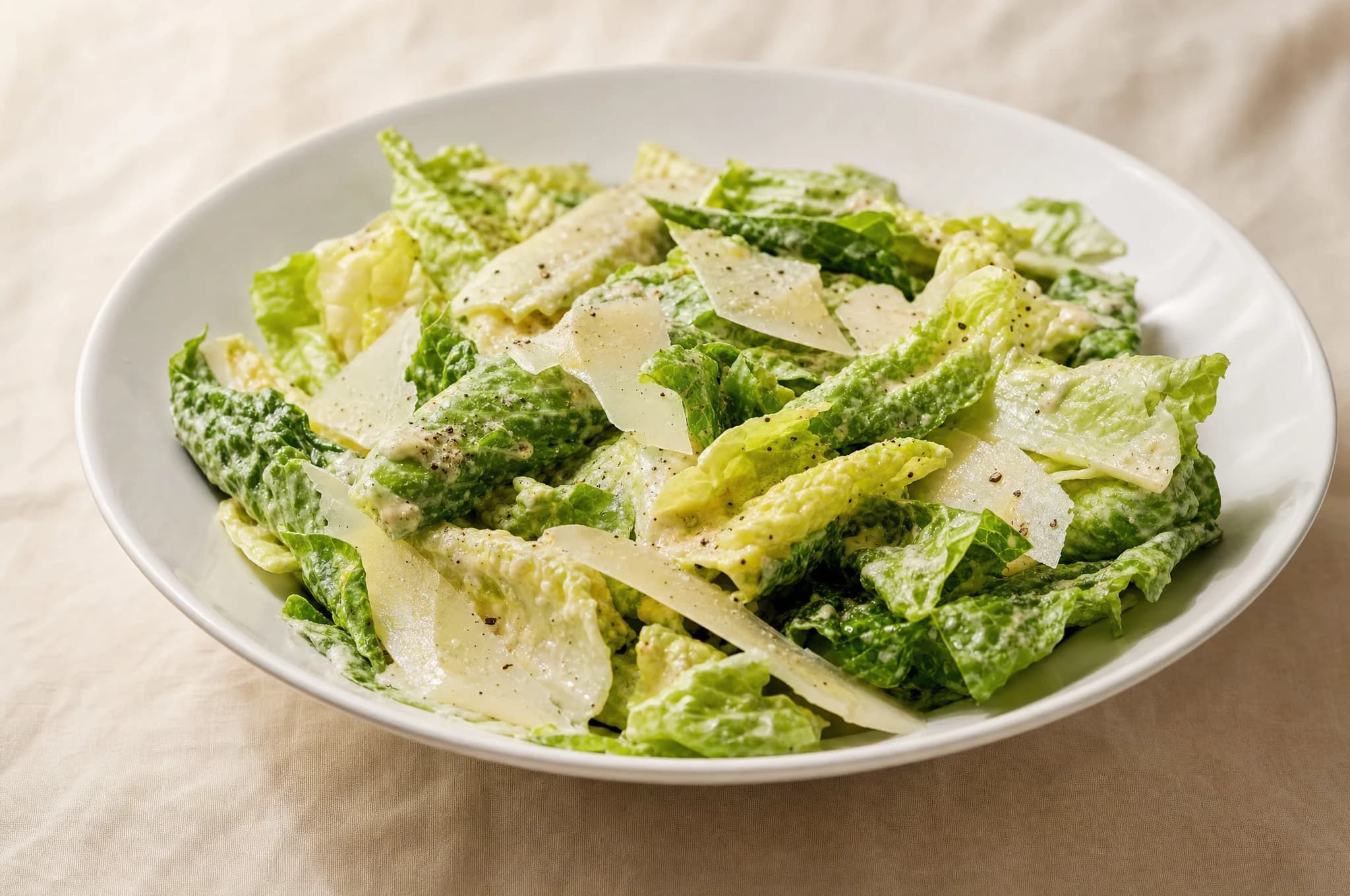 A keto Caesar salad in a wide white bowl with romaine, shaved Parmesan, and no croutons