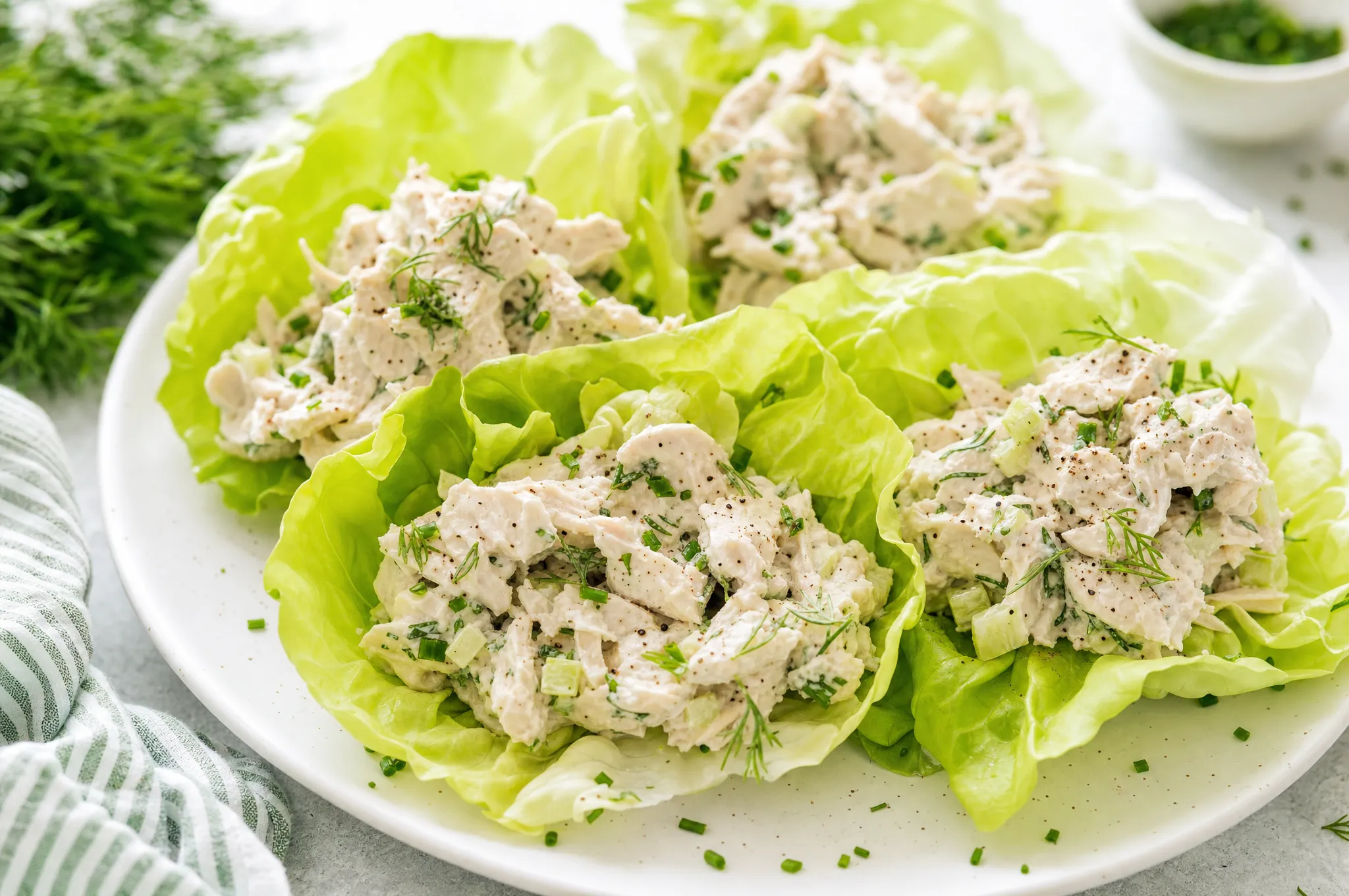 Creamy keto chicken salad with celery and fresh herbs served in crisp lettuce cups on a plate