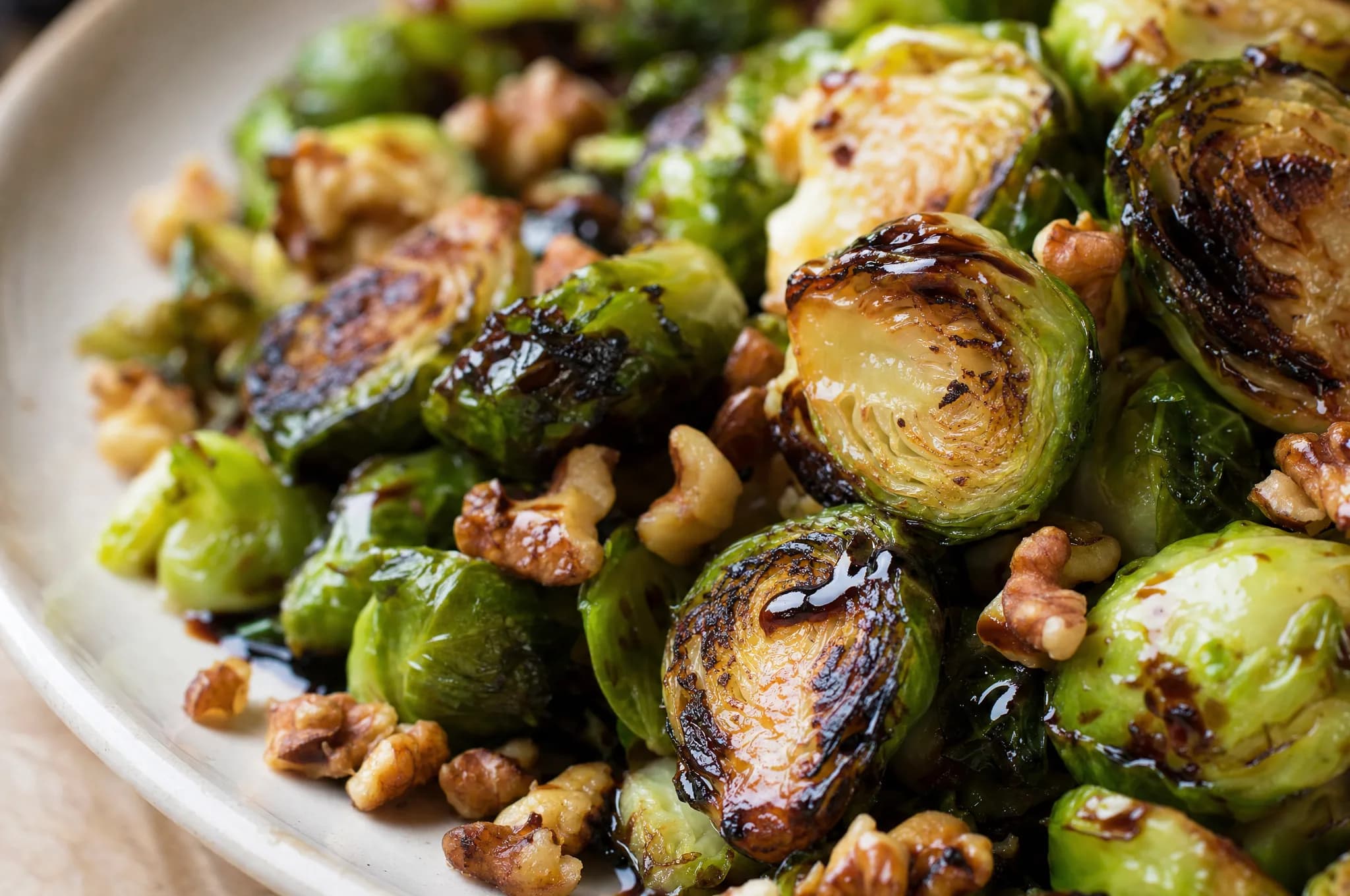 Roasted halved Brussels sprouts browned and crisp on a sheet pan, tossed with toasted walnut pieces and a glossy balsamic drizzle
