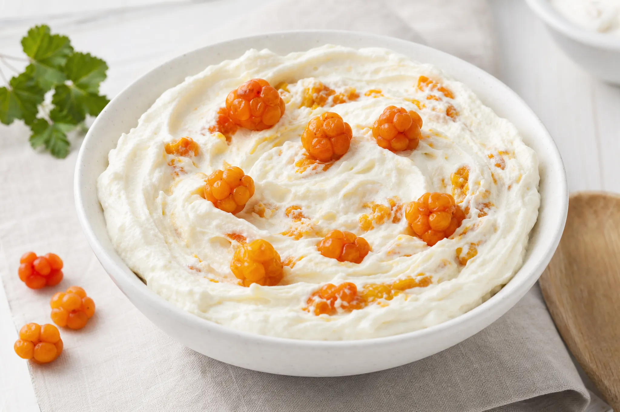 White bowl of Nordic cloudberry cream with golden-orange cloudberries folded through lightly whipped cream