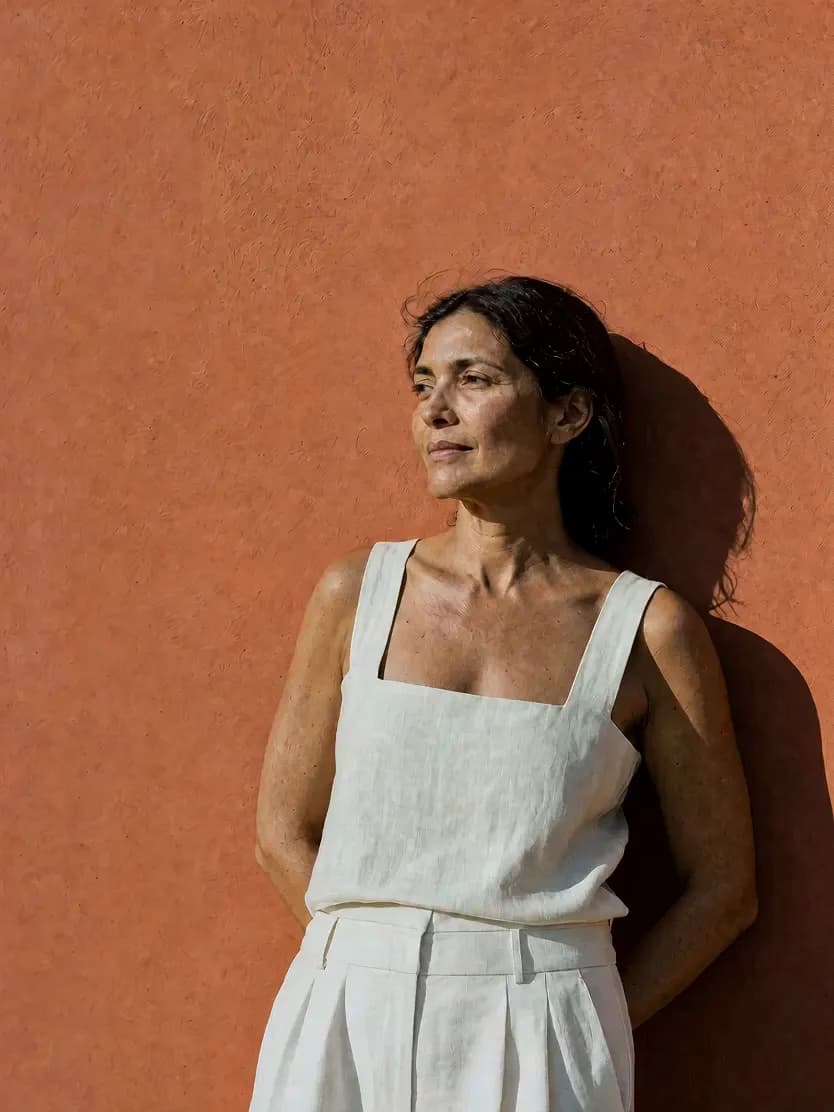 A woman leaning against a terracotta wall in warm afternoon light