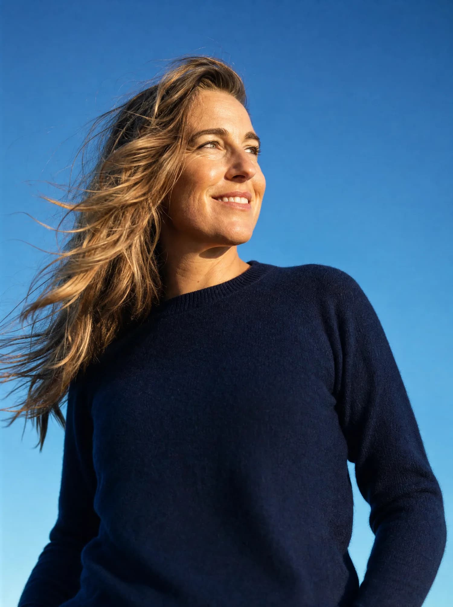 A woman smiling outdoors in natural light, holding a phone, representing the Nordic Diet Companion app